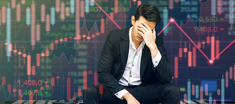 Stressed trader sitting in front of falling charts after a losing streak