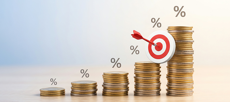 Rising stacks of coins with percent signs above them and a dart in the bullseye of a target leaning against the tallest stack