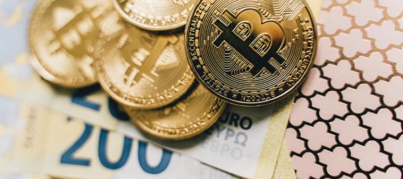Physical bitcoin tokens resting on euro banknotes, symbolising digital currencies meeting traditional money