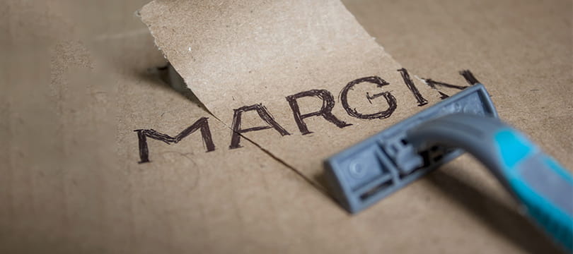 The word MARGIN handwritten on cardboard, partly shaved away by a razor