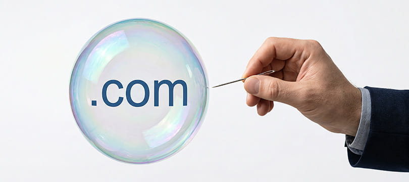 A hand popping a soap bubble marked dot com, symbol of the internet bubble