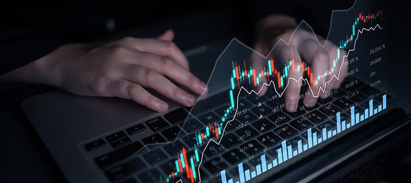 Trader comparing charts of different markets on multiple screens